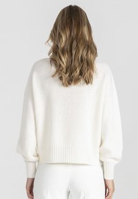 Biały, dziany sweter o luźnym kroju, z opadającymi ramionami, prążkowanymi mankietami i dołem. Miękka faktura, długość do połowy brzucha oraz minimalistyczny design.