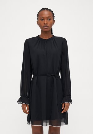 Black dress with long, pleated sleeves, a buttoned neck, and adjustable tie waist. Sheer skirt with contrasting white hem detail.