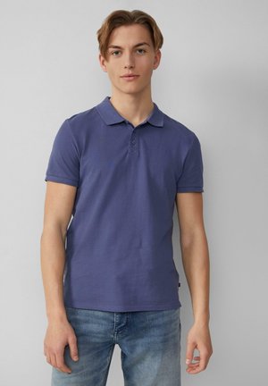 Polo shirt in marineblauw, korte mouwen, knoopsluiting en kraag. Glad katoen materiaal, slim-fit ontwerp, gecombineerd met lichtblauwe jeans.
