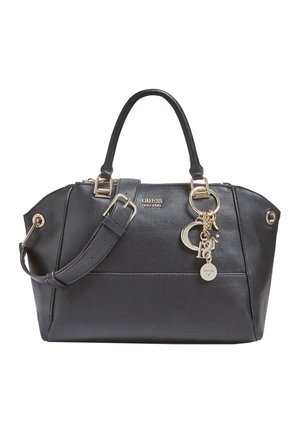 Czarna torebka Guess z dwoma uchwytami, regulowanym paskiem na ramię, złotym logo oraz zawieszkami w kształcie gwiazdy, półksiężyca i kółka.