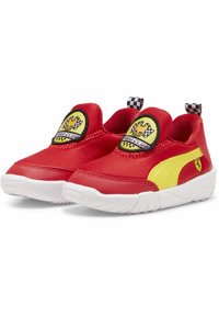 Piros szövet slip-on cipők sárga részletekkel, kerek folttal, amelyen egy rajzfilmfigura látható, valamint kockás részletek a húzófülön.