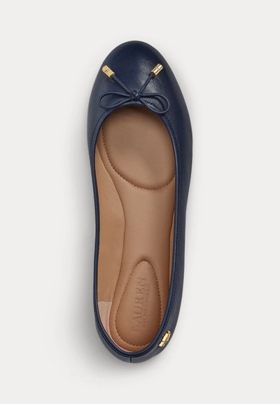 Ballerine en cuir bleu marine avec semelle intérieure rembourrée couleur fauve, petit nœud avec embouts dorés à l'avant et détail du logo doré près du talon.