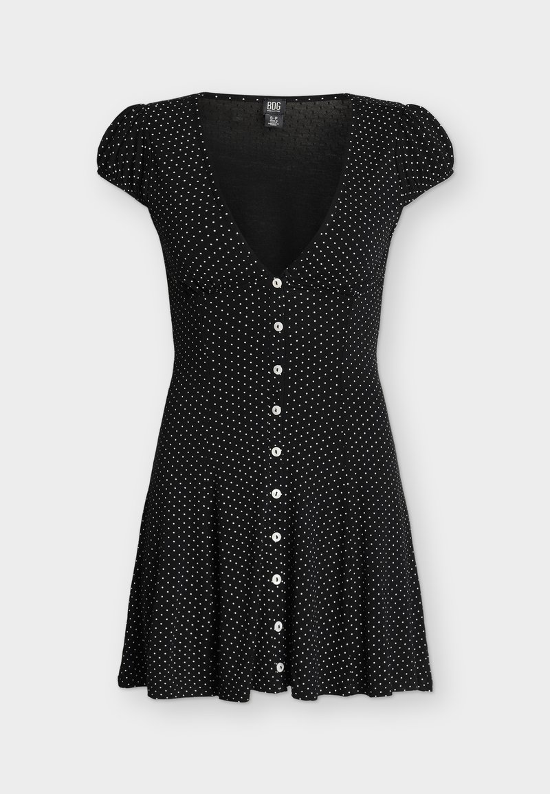 Μαύρο κοντό φόρεμα με λευκά πουά, ντεκολτέ σε σχήμα V, φουσκωτά κοντά μανίκια και λευκά κουμπιά μπροστά.