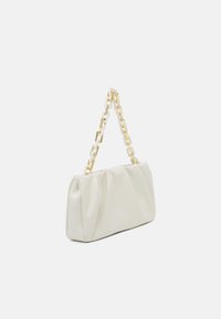 Sac pochette blanc avec une surface douce et texturée et une bandoulière chaîne dorée composée de gros maillons avec des accents blancs. Fronces à l'ouverture.