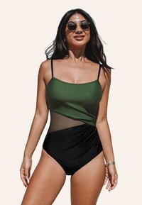 Maillot de bain une pièce avec un haut vert à fines bretelles, un détail en maille, et un bas noir avec un design froncé. Texture lisse tout au long.