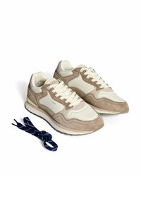 Beige und cremefarbene Sneaker aus Wildleder und Mesh-Materialien, mit einer dicken Sohle und cremefarbenen Schnürsenkeln. Enthält zusätzliche navyfarbene gemusterte Schnürsenkel.