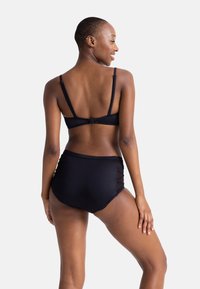 Juodas bikini rinkinys, kurį sudaro braletas su reguliuojamomis petnešėlėmis ir aukšto juosmens dugnas su permatomais šonais. Lygus paviršius, minimalistinis dizainas.