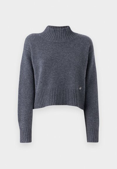 Pull court gris foncé en tissu doux, avec un col montant à côtes et un ourlet à côtes, orné d'un petit logo argenté sur le côté.