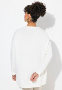 Maglione bianco oversize a maglia con scollatura rotonda e spalle scese. Tessuto morbido, maniche lunghe e orlo curvo sul retro.