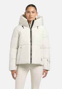 Giacca a vento bianca con un grande cappuccio, zip nera e due tasche davanti. Presenta un motivo trapuntato e un logo sulla manica.