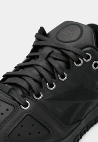 Sapatilhas atléticas pretas feitas de couro e borracha. Apresentam um design texturizado, ilhós em metal e um logótipo em relevo na lingueta.