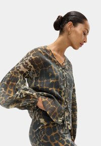Langärmlige Bluse aus leichtem, gemustertem Stoff mit einem grünen und braunen Leopardenmuster, einem V-Ausschnitt und gerafften Manschetten.