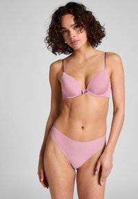 Soutien-gorge rose et culotte taille haute assortie, texture lisse avec bretelles réglables. Présente un nœud décoratif au centre. Design simple.