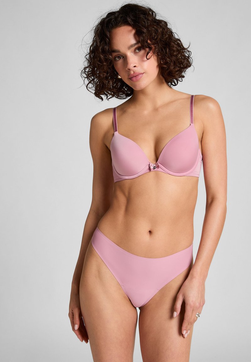 Soutien-gorge rose et culotte taille haute assortie, texture lisse avec bretelles réglables. Présente un nœud décoratif au centre. Design simple.