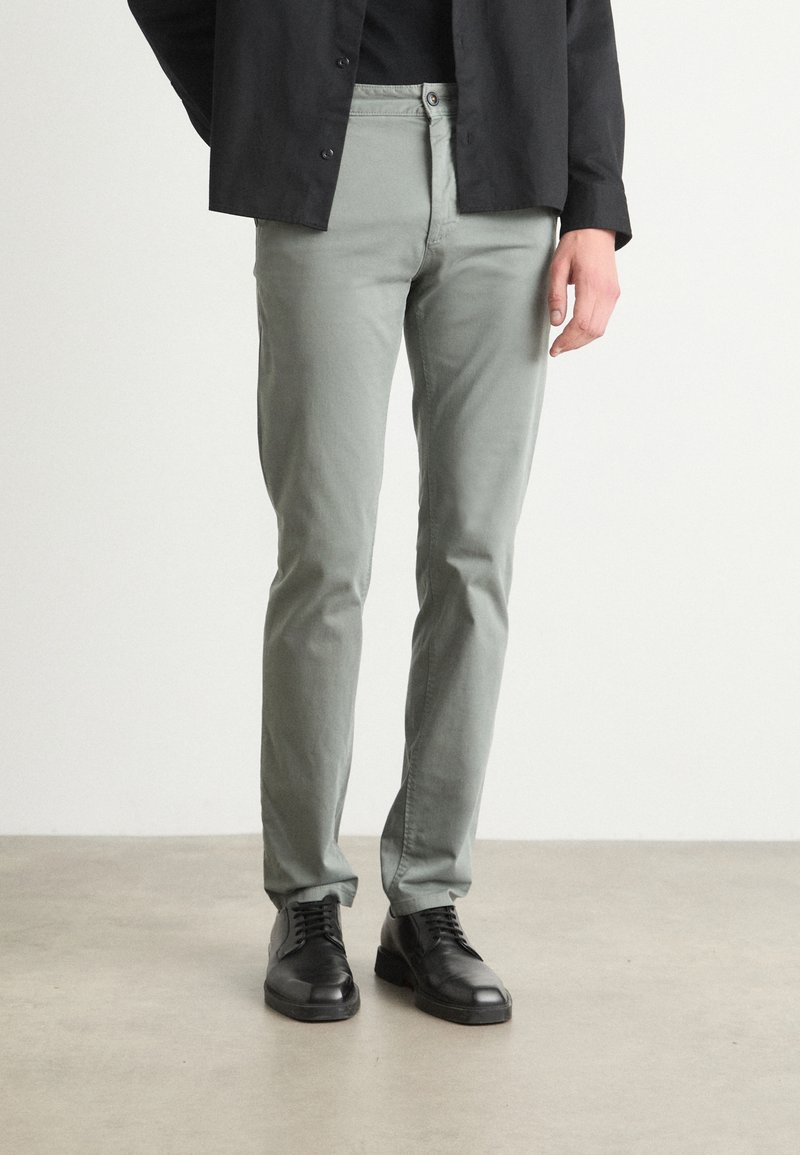 Pantaloni slim-fit de culoare gri deschis, din bumbac, cu o textură netedă, prezentând un design clasic cu cinci buzunare și închidere cu buton.