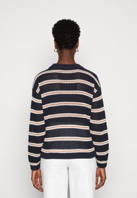 Sweter z dzianiny w granatowym kolorze z poziomymi paskami w białym i rdza iwym. Posiada okrągły dekolt i ściągacze na mankietach. Luźna struktura tkana.