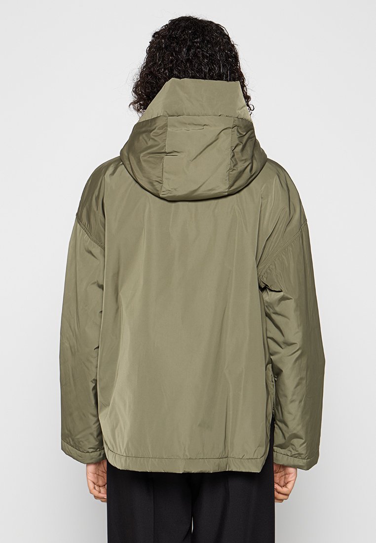 Olivgrüne Steppjacke mit Kapuze, die eine glatte Textur, eine große Rückenpasse und eine entspannte Passform aufweist. Keine sichtbaren Beschläge oder Akzente.