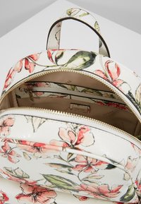 Rugzak met bloemenpatroon in wit met roze en groene accenten, voorzien van een ritssluiting, binnenvakken en een draaghendel.