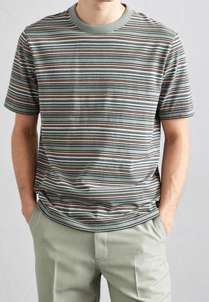 Koszulka z krótkim rękawem w paski w stonowanym zielonym kolorze, z poziomymi paskami w kolorach granatowym, białym i rdzawym. Okrągły dekolt, miękka bawełniana tekstura.