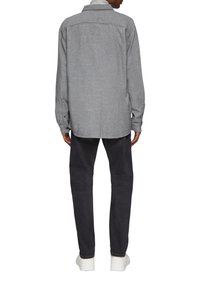 Grijze lange mouwen overhemd met knopen, een kraag, textuurstof en een afgeronde zoom, gecombineerd met donkere broek en witte sneakers.