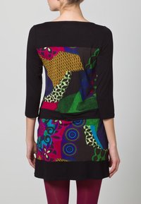 Černé šaty s tříčtvrtečními rukávy, které mají multicolor geometrický a květinový vzor, kombinující různé textury a živé barvy.