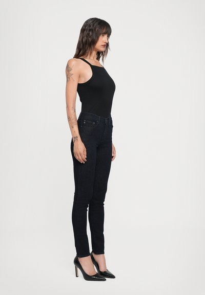 Schwarzer ärmelloser Body kombiniert mit dunkelblauen Slim-Fit-Jeans und schwarzen spitzen Absätzen, mit einer glatten Textur und klassischem Design.