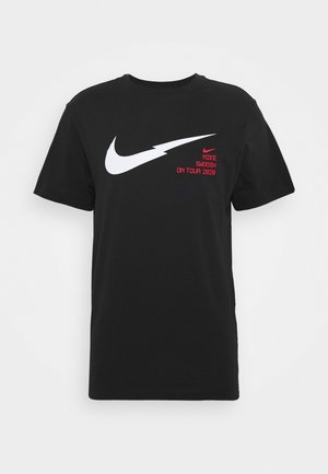 T-shirt noir à manches courtes avec un grand Swoosh Nike blanc en forme d'éclair et le texte rouge "NIKE SWOOSH ON TOUR 2020" sur la poitrine.