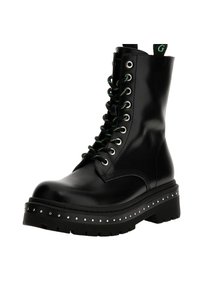 Botte de combat en cuir noir avec des lacets verts, clous en argent sur la semelle, et une plateforme épaisse. Présente un bout arrondi et un design à lacets.