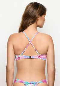 Top de bikini cu model floral, cu bretele ajustabile în cruce, în culori pastelate. Are un închizător la spate și o textură de material neted.