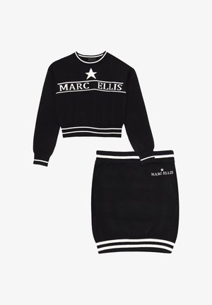 Set composto da maglione corto nero e gonna a tubino con strisce bianche e testo "MARC ELLIS". Il maglione ha maniche lunghe e un accento a stella.