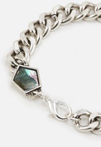 Pulseira de corrente de metal prateado com um detalhe de pedra labradorite hexagonal e fecho tipo lagosta. Elos texturizados distintivos criam um interesse visual.