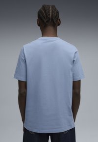 Lyseblå kortærmet T-shirt lavet af blød bomuld, med en klassisk rund hals og en afslappet pasform, uden synlige logoer eller mønstre.