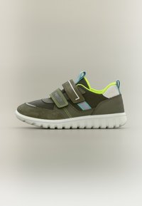 Παιδικό αθλητικό παπούτσι σε ελιά πράσινο με νεον κίτρινη επένδυση, μπλε λεπτομέρειες, δύο αυτοκόλλητα Velcro και λευκή υφή σόλα σε ουδέτερο φόντο.