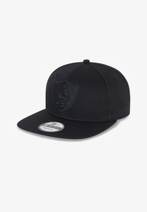 Gorra snapback negra con un logo de los Raiders en relieve en la parte frontal, visera plana y una pegatina circular del tamaño en la visera.