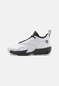 Białe buty sportowe z czarnymi akcentami, wyściełanym siateczkowym kołnierzem, sznurówkami i teksturowanym wierzchem. Posiada widoczną jednostkę Air i detale logo.