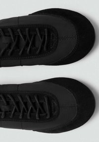 Calzature nere realizzate con un mix di materiali in suede e tessuto. Punta arrotondata, sistema di allacciatura prominente e dettagli cuciti in tutta la scarpa.