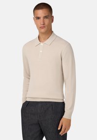 Beiger, gestrickter Polopullover mit langen Ärmeln, Kragenverleihen, einer Knopfleiste mit drei Knöpfen sowie gerippten Manschetten und Saum. Glatte Textur, körperbetontes Design.