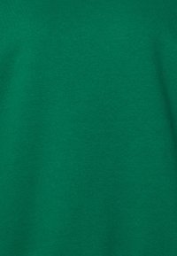 Camiseta de algodón verde con un acabado liso y texturizado. Mangas cortas y escote redondo, sin patrones ni acentos visibles.
