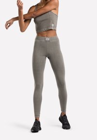 Grå atletisk crop top med tunna axelband, matchad med högmidjade grå leggings. Båda gjorda av elastiskt material med en subtil textur och logodetalj.