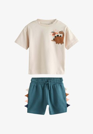 Krémové tričko s farebnou grafikou dinosaura a textom. Tyrkysové šortky majú bočné akcenty v odtieňoch modrej, terrakotovej a ružovej.