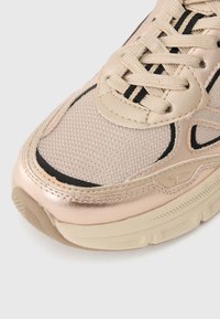Hellbeige Sneaker mit metallisch roségoldenen Akzenten, Netzstruktur, Schnürdesign und schwarzen Streifen an den Seiten und am oberen Rand.