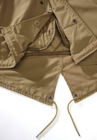 Interno di giacca color tan con chiusura a zip, due bottoni e coulisse regolabile. Presenta una texture di tessuto morbido e dettagli di cucitura rinforzata.