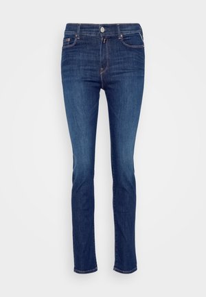 Sötétkék farmernadrág, slim fit kivitelben, öt zsebből áll és narancssárga varrással ellátott. Elöl gombos és cipzáras záródással rendelkezik.