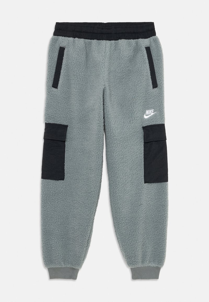 Šedé flísové tepláky Nike s černým elastickým pasem, černými bočními a cargo kapsami, žebrovanými manžetami a bílým logem Nike na pravém stehně.
