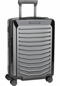 Valigia rigida grigia con scanalature orizzontali, manico telescopico e quattro ruote girevoli per una facile manovrabilità.
