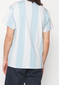 Tričko s krátkým rukávem s horizontálními světlomodrými a bílými pruhy, vyrobené z bavlny, s volným střihem a designem kulatého výstřihu.