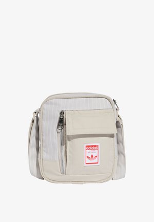 Borsa a tracolla in tela beige con righe verticali, tasca frontale con zip e patch del logo rosso Adidas. Tracolla regolabile per versatilità.