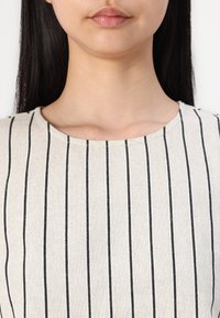 Cream fabric with black vertical stripes; round neckline; soft texture, plain design, suitable for casual wear, minimalistic style.