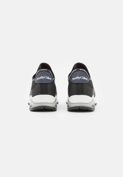 Zwarte sportschoenen met witte zolen, met een gladde textuur, logo-details op de hakken en een gestroomlijnd ontwerp.