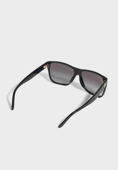 Lunettes de soleil rectangulaires noires, avec des verres gris dégradés et des détails dorés, présentées ouvertes sur un fond clair.